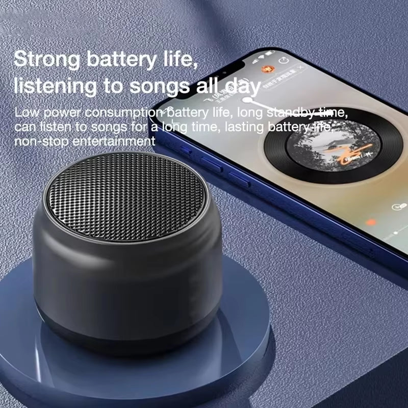 Compact black wireless speaker beside smartphone playing music, highlighting strong battery life and all-day listening